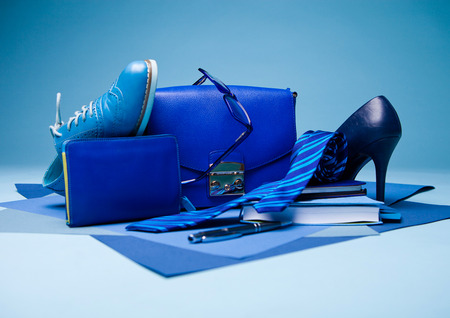 Blue color fashion style still life setup on blue background with shoe tie glasses bag pen and notebookの写真素材