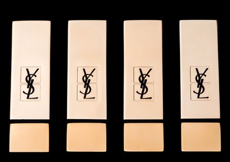 LONDON, UK - SEPTEMBER 21, 2017: Golden containers of luxury Yves Saint Laurent lipstick on black  backgroundのeditorial素材