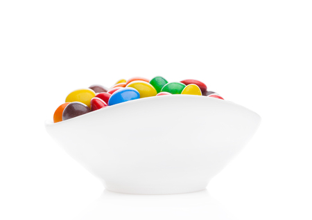 Round colorful coated sweet candies in white bowl on white backgroundの写真素材