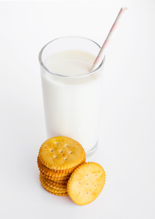 Glass of milk with round cheese crackers on white backgroundの写真素材