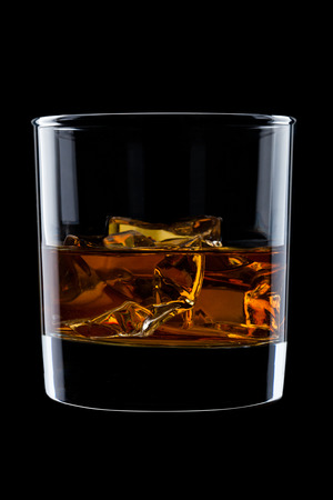 Elegant glass of whiskey with ice cubes isolated on black backgroundの写真素材