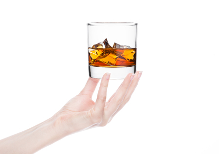 Female hand holding whiskey glass with ice on white background. の写真素材