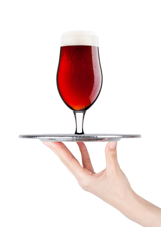 Hand holds tray with cold red ale beer with foam on white backgroundの写真素材