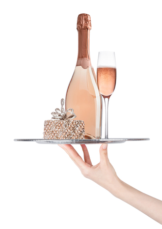 Hand holds tray with champagne bottle and glass with golden gift box on white backgroundの写真素材