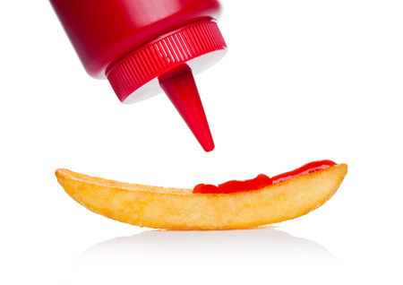 Crispy french fries potato macro with ketchup container on white backgroundの写真素材