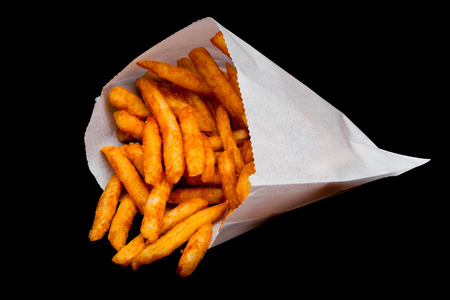Southern french fries with paprika and salt in paper bag container on black background