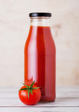 Glass bottle of tomato paste with raw fresh organic tomato on wooden backgroundの写真素材