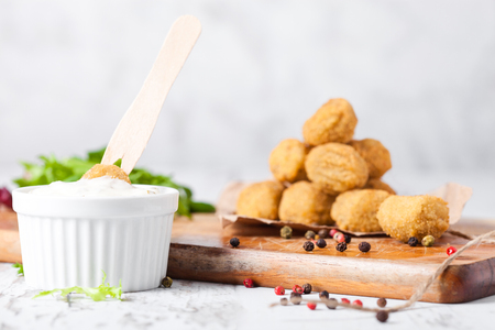 Fried crispy chicken popcorn with fresh salad and sauce on chopping board on wooden backgroundの写真素材