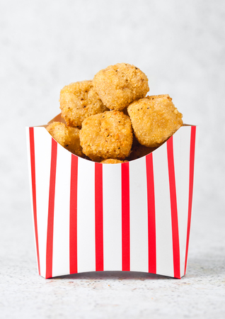 Paper container with fried crispy chicken popcorn nuggets on marble backgroundの写真素材