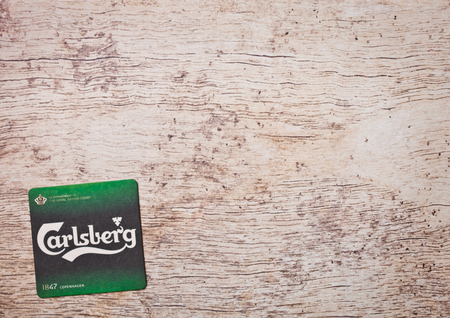 LONDON, UK - MARCH 22, 2018:  Carlsberg 1664 Beer beermat coaster on wooden background