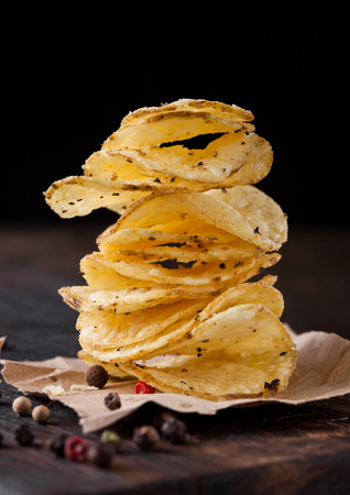 Crispy delicious pepper potato crisps chips snack on dark wooden board and brown paperの写真素材