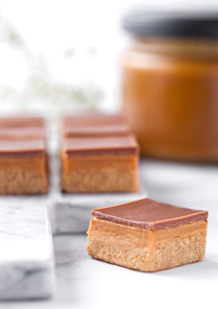 Caramel and biscuit shortcake bites dessert on marble board with jar of salted caramelの写真素材