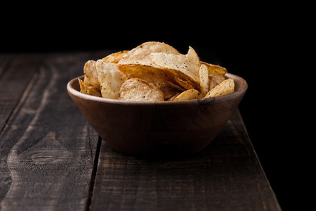 Crispy delicious pepper crisps in wooden bowl on wooden backgroundの写真素材