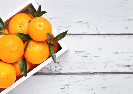 White wooden box with fresh raw organic oranges on light wooden background.Top view.の写真素材