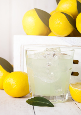 Glass of organic fresh lemon juice with raw lemons in white wooden boxの写真素材