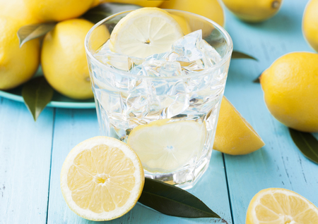 Glass of organic fresh lemon still summer water with raw lemons on blue wooden background.Top viewの写真素材