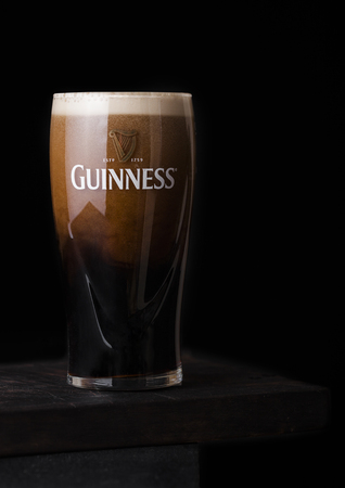 LONDON, UK - APRIL 27, 2018: Original glass of Guinness draught stout beer bottle on darkwooden...