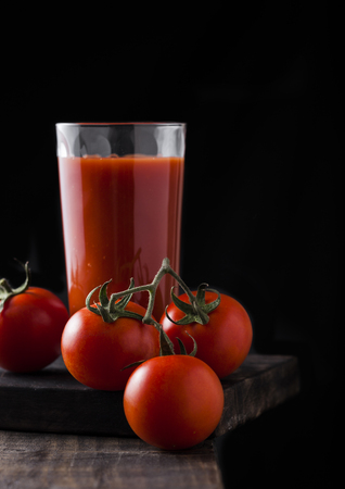 Glass of tomato juice with fresh raw tomatoes on wooden backgroundの写真素材