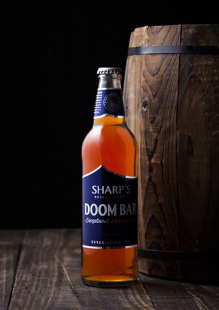LONDON, UK - MAY 03, 2018: Cold bottle of Sharp's Doom Bar amber ale on with wooden barrel on dark background.のeditorial素材