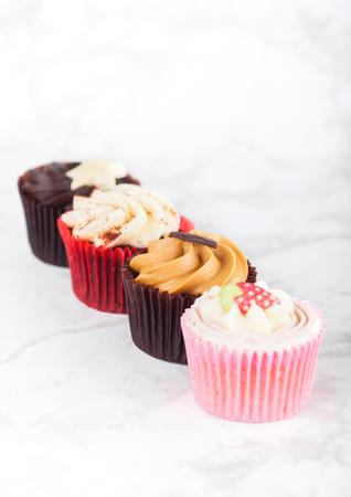 Fresh cupcake muffins with caramel and chocolate, strawberries and toffee on marble boardの写真素材