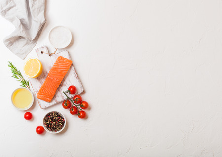 Plastic container with fresh salmon slice with oil tomatoes and lemon on stone kitchen backgroundの写真素材