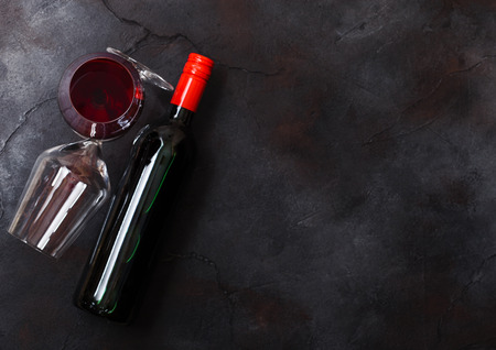Elegant glass and bottle of red wine on kitchen table background.