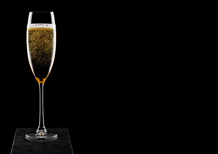 Elegant glass of yellow champagne with bubbles on black marble board on black background.の写真素材