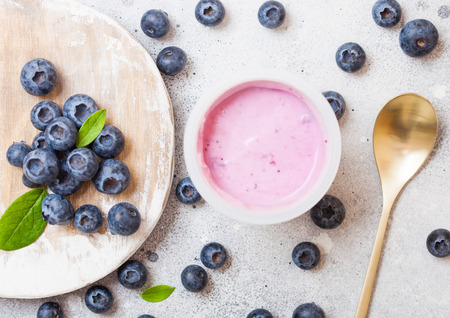 Fresh homemade blueberry yogurt with fresh berries on wooden board and golden spoon. Top viewの写真素材