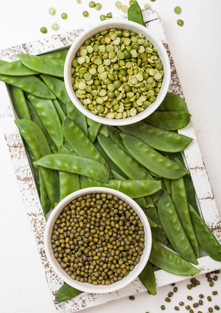 Bowl of  mung beans and split peaswith raw organic mangetout in vintage wooden box on white kitchen backroundの写真素材