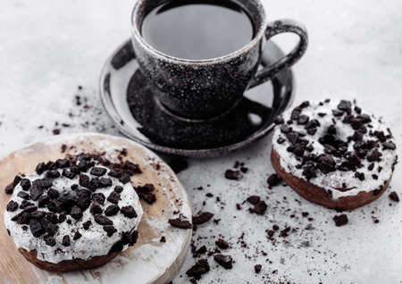 Black coffee cup with saucer and doughnuts with black cookies on stone kitchen table background.の写真素材