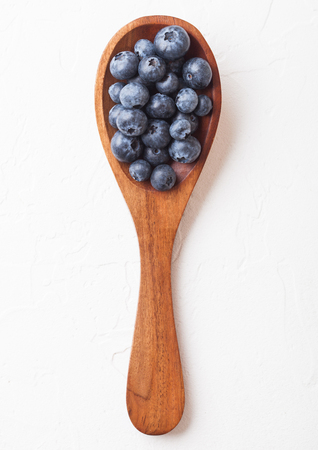 Fresh raw organic blueberries on wooden spoon on white kitchen background. Food concept.の写真素材