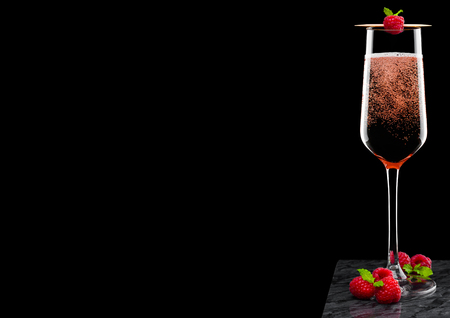 Elegant glass of pink rose champagne with raspberry on stick with fresh berries and mint leaf on black marble board on black background.の写真素材