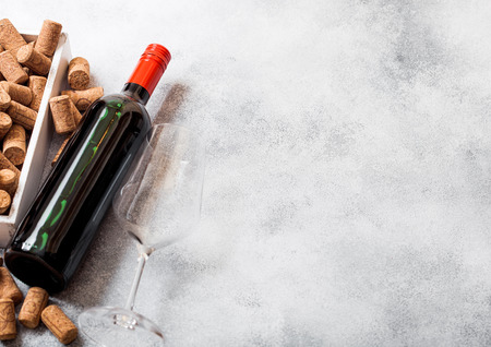 Elegant glass and bottle of red wine with corks on kitchen table background.の写真素材