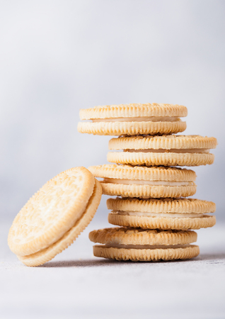 Sandwich cookie consisting of two chocolate wafers with cream filling with glass of milk on stone board.の写真素材