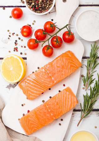 Plastic container with fresh salmon slice with oil tomatoes and lemon on wood kitchen backgroundの写真素材