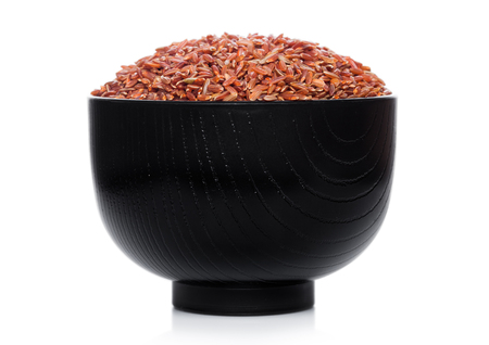 Black bowl of raw organic red rice on white background.の写真素材