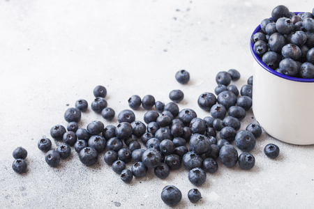 Fresh raw organic blueberries with leaf in white cup from enamel on white background.の写真素材