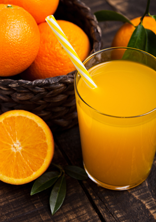 Glass of organic fresh orange smoothie juice with raw oranges on dark wooden backgroundの写真素材