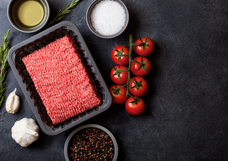 Tray with raw minced homemade beef meat with spices and herbs. Top view and space for text. On...