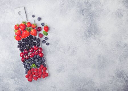 Fresh organic summer berries mix on white marble board on light kitchen table background. Raspberries, strawberries, blueberries, blackberries and cherries. Top viewの写真素材