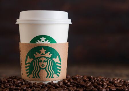 LONDON, UK - JUNE 05, 2019: Starbucks Coffee Paper Cup for take away with coffee beans on wooden background.のeditorial素材