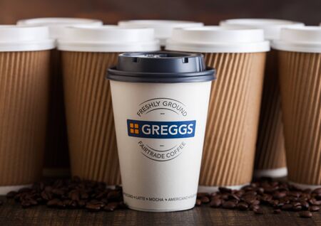 LONDON, UK - JUNE 05, 2019: Greggs Coffee Paper Cup for take away with coffee beans on wooden background with brown coffee cups.のeditorial素材