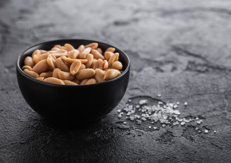 Salted and roasted peanuts classic snack in black bowl on black table.の写真素材