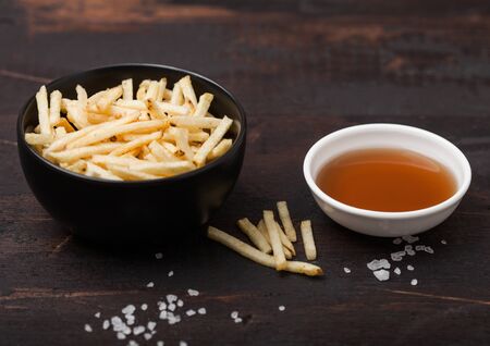 Salt and vinegar potato sticks in white bowl, classic snack with ketchup on wood.の写真素材