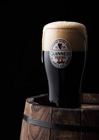 LONDON, UK - APRIL 27, 2018: Original glass of Guinness original stout beer on top of old wooden barrel. Guinness beer has been produced since 1759 in Dublin, Ireland.のeditorial素材