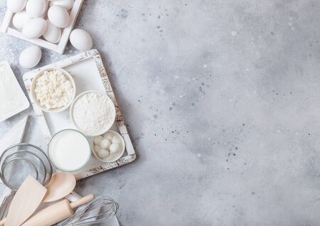 Fresh dairy products on white table background. Glass of milk, bowl of flour and cottage cheese and eggs. Box of baking utensils. whisk and spatula in vintage wooden box.Top view.の写真素材