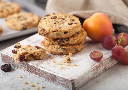 Homemade organic oatmeal cookies with raisins and apricots with baking tray on light kitchen background.の写真素材