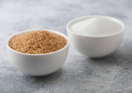 White bowl plates of natural brown and white refined sugar on light background.の写真素材
