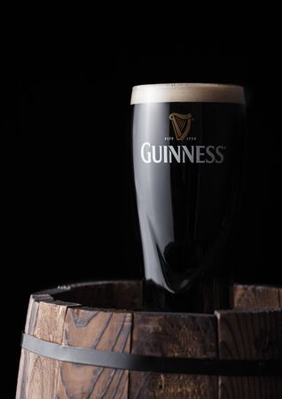LONDON, UK - APRIL 27, 2018: Original glass of Guinness draught stout beer on top of old wooden barrel. Guinness beer has been produced since 1759 in Dublin, Ireland.のeditorial素材