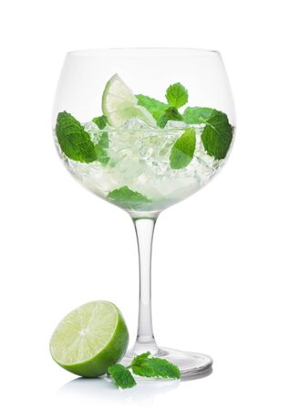Luxury glass of Mojito summer alcoholic cocktail with ice cubes mint and lime on white background with raw limeの写真素材